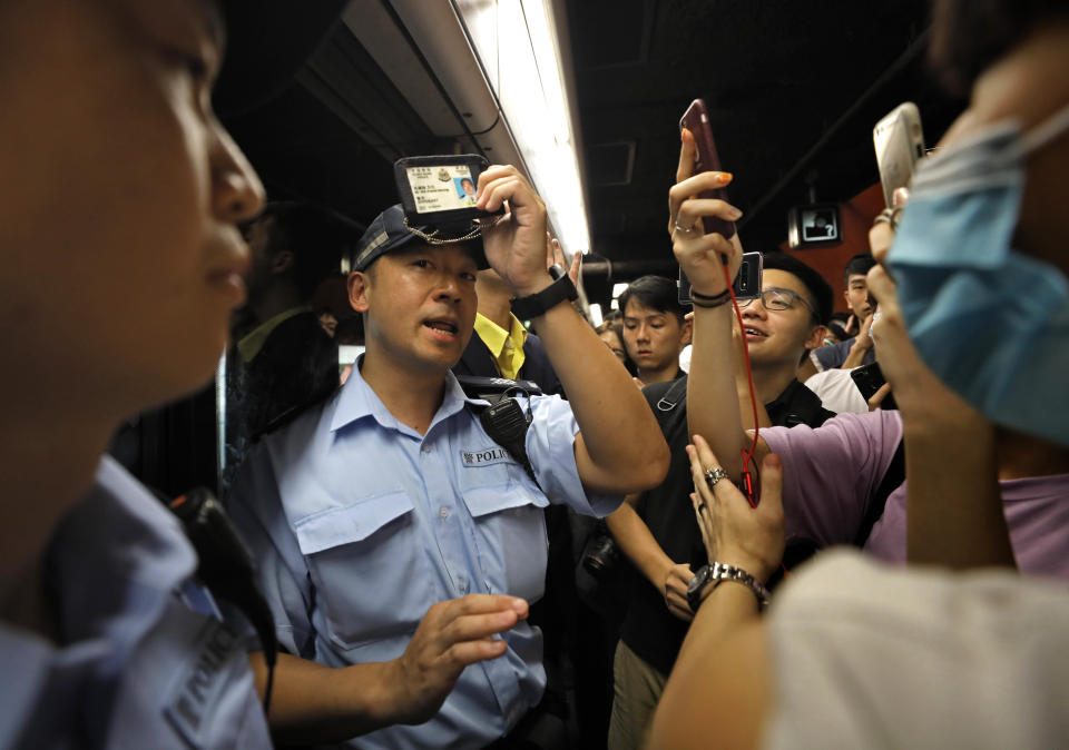 A police officer shows his warrant card after protesters requested at a subway platform in Hong Kong Tuesday, July 30, 2019. Protesters in Hong Kong have disrupted subway service during the morning commute by blocking the doors on trains, preventing them from leaving the stations. (AP Photo/Vincent Yu)