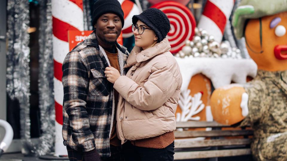 young interracial couple walks at christmas fair on street against background of decoration concept of love relationships and unity between different human races