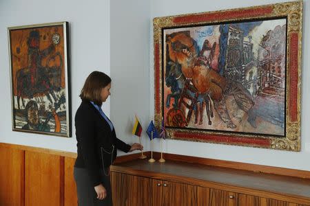 Embassy intern Leva Andrukaityte poses with the artworks "Man on a Bull" (L) and "Odalisque of the Grand Canal" by artist Theo Tobiasse, at the Embassy of Lithuania in London December 8, 2014. REUTERS/Luke MacGregor