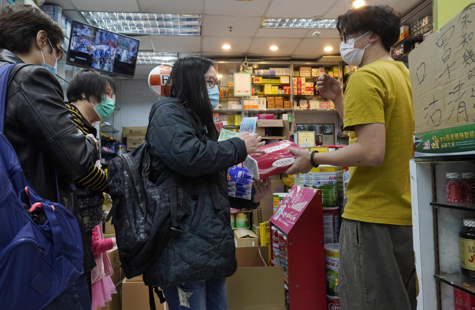 People wearing face masks queue up to purchase tissue papers at a pharmacy in Hong Kong, Thursday, Feb. 6, 2020. Ten more people were sickened with a new virus aboard one of two quarantined cruise ships with some 5,400 passengers and crew aboard, health officials in Japan said Thursday, as China reported 73 more deaths and announced that the first group of patients were expected to start taking a new antiviral drug. (AP Photo/Vincent Yu)