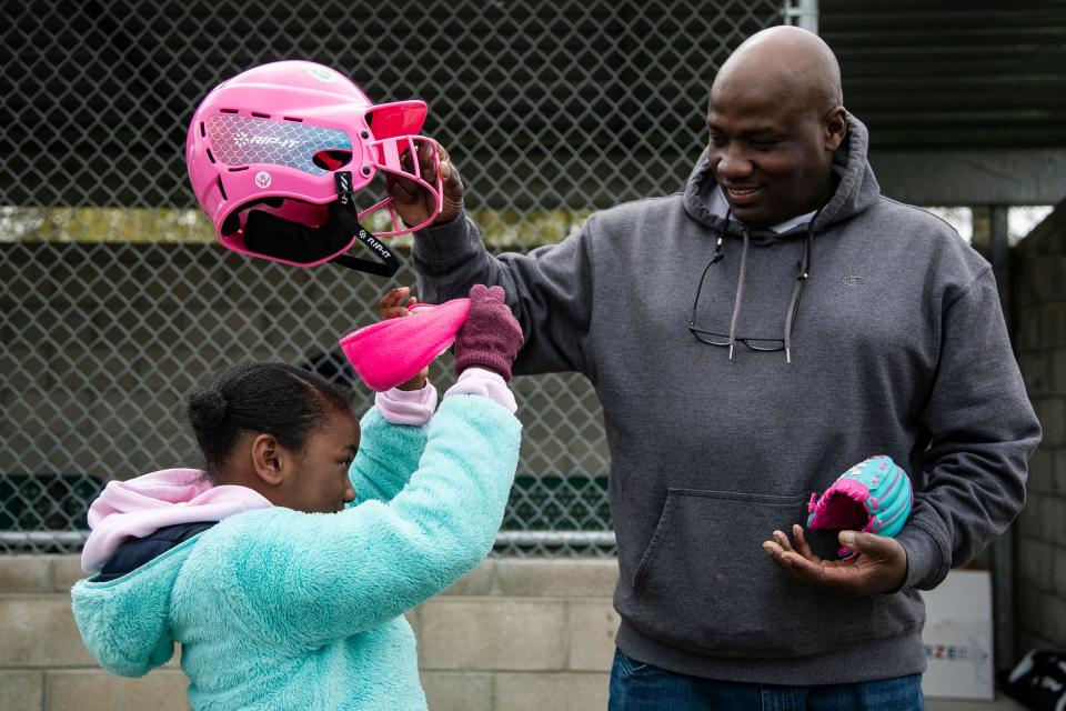 Christopher Dixon, right, helps put a baseball helmet on his daughter Honor, 7, before batting at practice at Stoepel Park in Detroit on Tuesday, April 25, 2023.