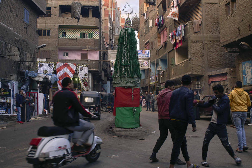 Residents pass by a Christmas tree made of recycled plastic and other material in a Coptic residential and industrial area of eastern Cairo, Egypt, Monday, Jan. 6, 2020. (AP Photo/Hamada Elrasam)