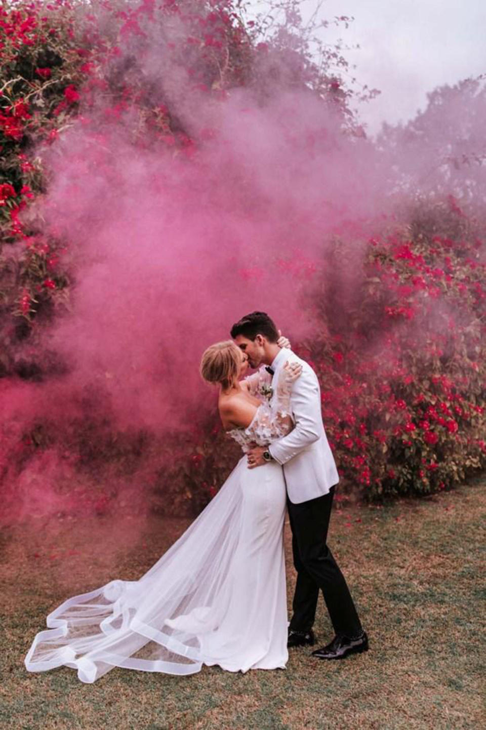 Bride Jess Dunbar kisses groom Matt Price in front of a cloud of pink smoke on their wedding day. Photo: supplied.