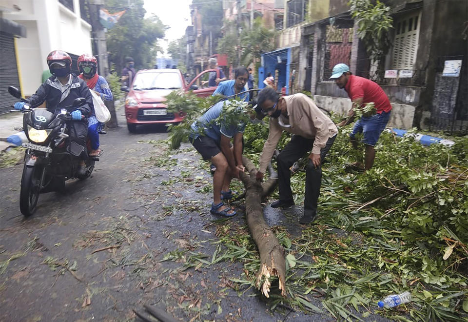 Locals clear tree branches that fell after cyclone Amphan hit the region, in Kolkata, India, Thursday, May 21, 2020. The powerful cyclone that slammed into coastal India and Bangladesh has left damage difficult to assess Thursday. (AP Photo/Bikas Das)