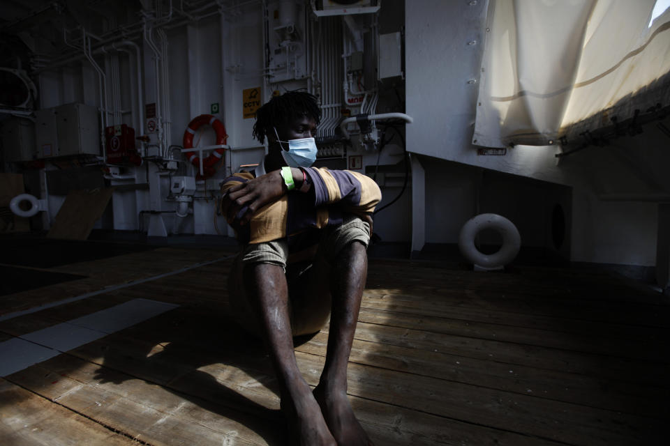 Mohamed Salah, a migrant from Ivory Coast, sits on the deck of the rescue vessel Geo Barents waiting for his disembarkation at the port of Augusta, on the island of Sicily, Italy, Monday, Sept. 27, 2021. Salah is among tens of thousands of migrants who have endured torture, sexual violence and extortion at the hands of guards in detention centers in Libya, a major hub for migrants fleeing poverty and wars in Africa and the Middle East, hoping for a better life in Europe. (AP Photo/Ahmed Hatem)