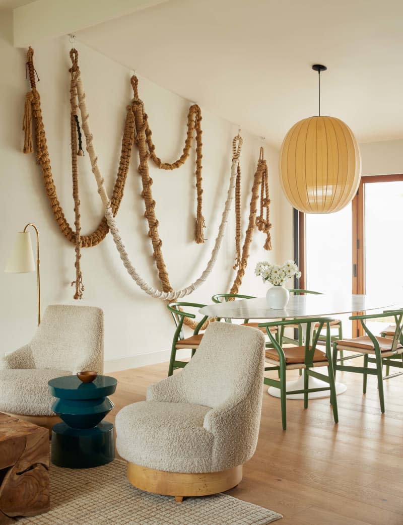 White boucle accent chairs, green and woven modern dining chairs, rope art installation, paper mache lighting fixture