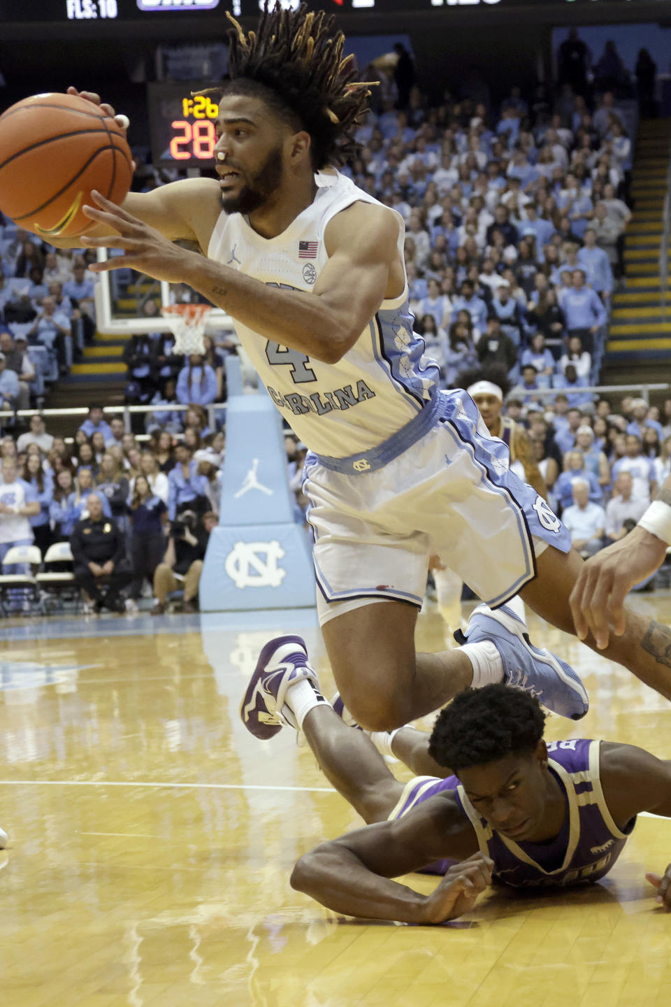 North Carolina guard R.J. Davis (4) manages to get a pass off as he stumbles over James Madison guard Xavier Brown during the second half of an NCAA college basketball game, Sunday, Nov. 20, 2022, in Chapel Hill, N.C. (AP Photo/Chris Seward)