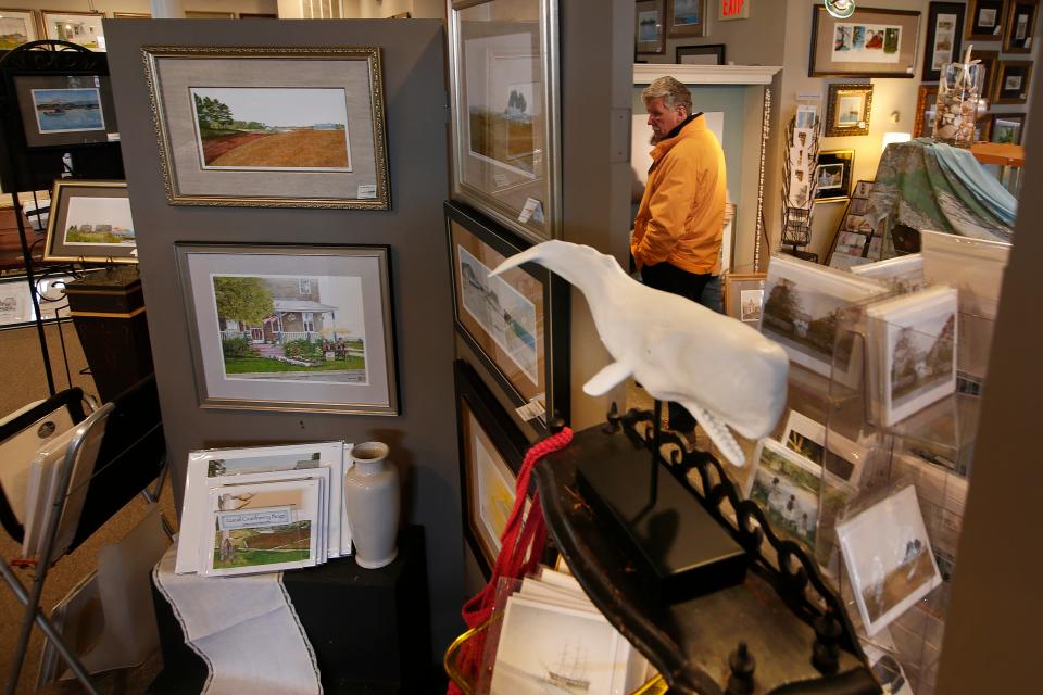 Customers pick some items to purchase at the Arthur Moniz Gallery on William Street in New Bedford which will close after twenty years.