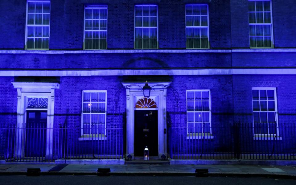 A candle lit at the doorstep of 10 Downing Street, illuminated in blue to celebrate the 72nd anniversary of the NHS - REUTERS/Peter Nicholls