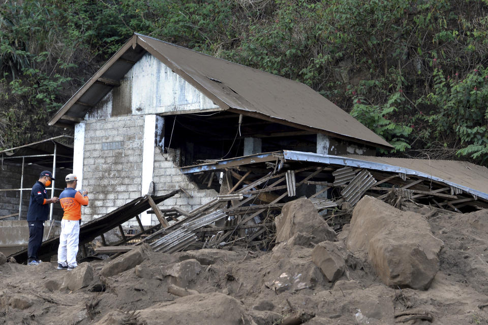 Rescuers inspect a house damaged by an earthquake-triggered landslide in Bangli, on the island of Bali, Indonesia, Saturday, Oct. 16, 2021. A few people were killed and another several were injured when a moderately strong earthquake and an aftershock hit the island early Saturday. (AP Photo/Dewa Raka)