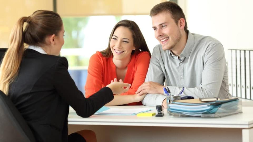 Happy couple being attended by office worker at office