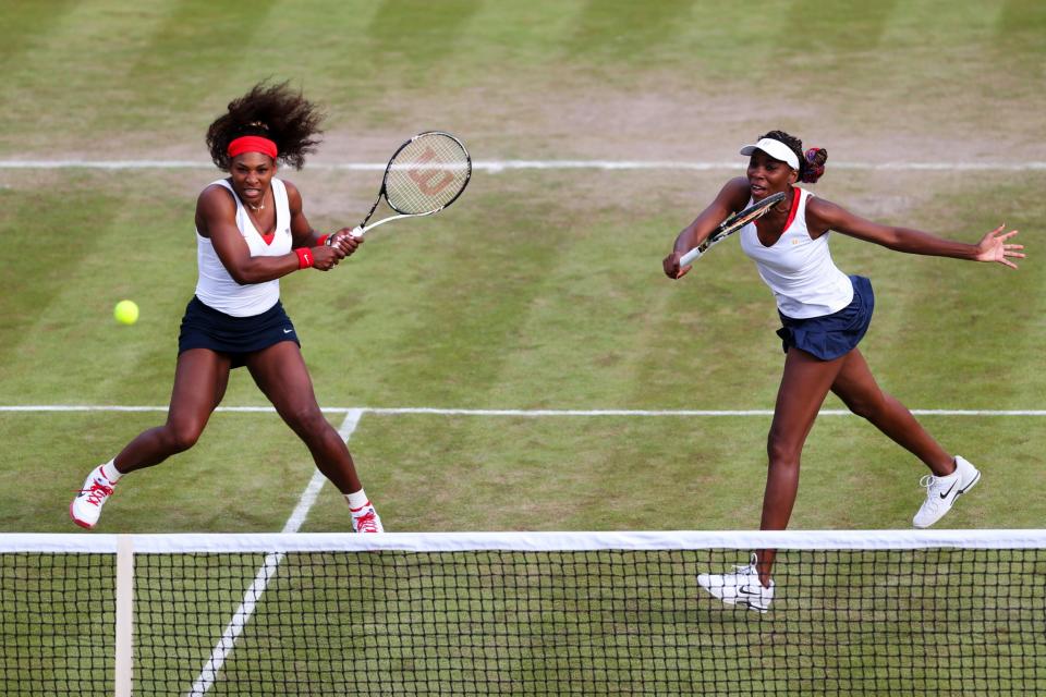 <p>Venus Williams (R) of United States hits a forehand next to her partner Serena Williams of the United States during their Women’s Doubles Tennis match against Sorana Cirstea and Simona Halep of Romania on Day 3 of the London 2012 Olympic Games at the All England Lawn Tennis and Croquet Club in Wimbledon on July 30, 2012 in London, England. (Photo by Clive Brunskill/Getty Images) </p>