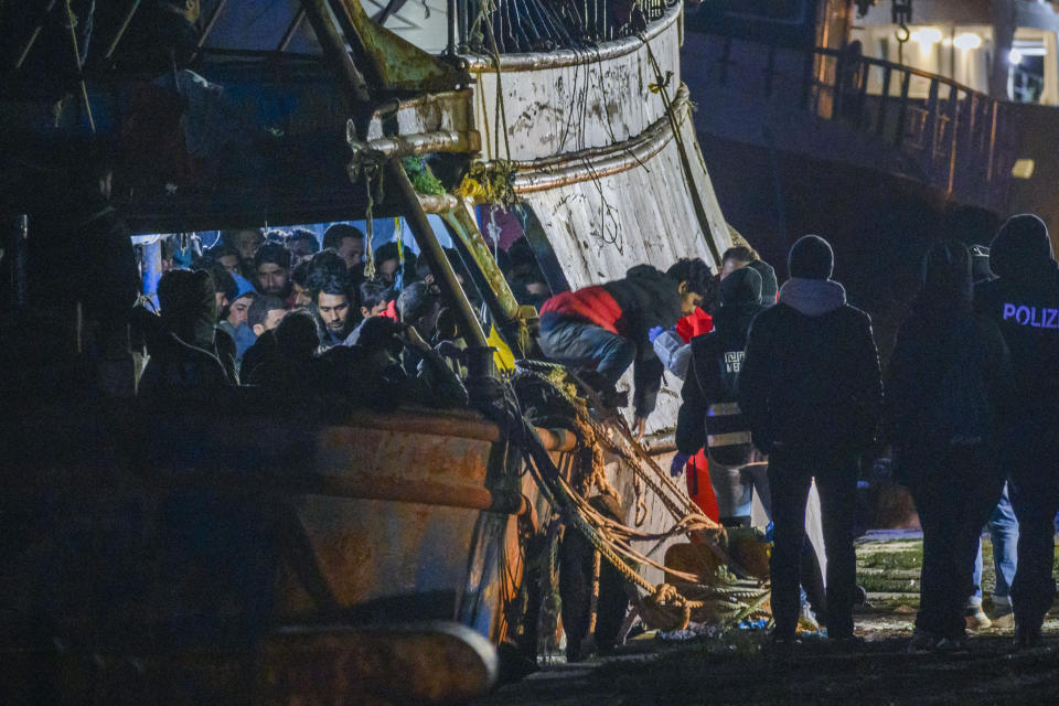 Some 500 migrants start disembarking from a fishing boat in the southern Italian port of Crotone, early Saturday, March 11, 2023. The Italian coast guard was responding to three smugglers boats carrying more than 1,300 migrants “in danger” off Italy’s southern coast, officials said Friday. Three small coast guard boats were rescuing a boat with 500 migrants about 70 nautical miles off the Calabria region, which forms the toe of the Italian boot. (AP Photo/Valeria Ferraro)