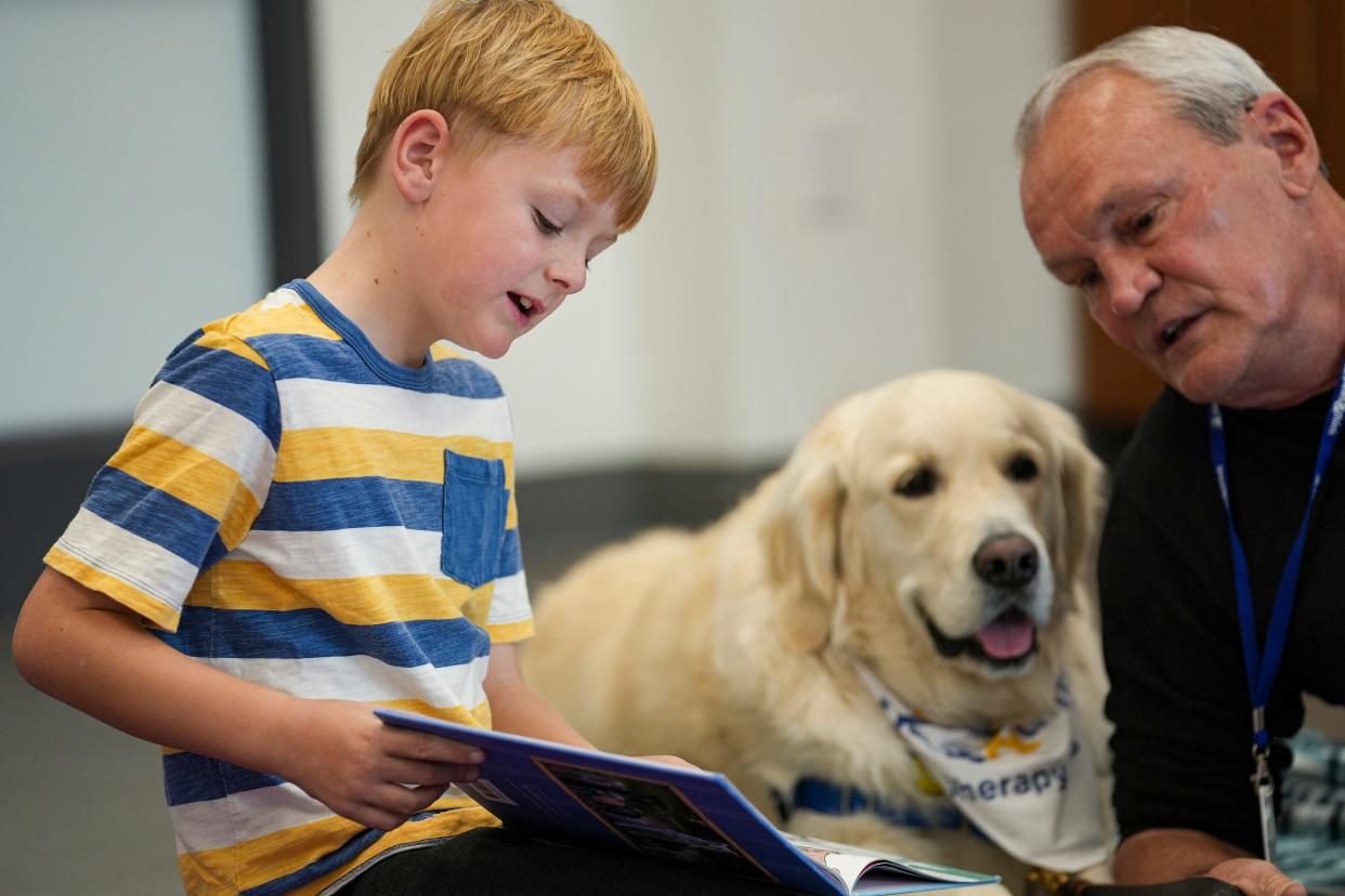 PJ Kelly, 8, reads to Paws and Think therapy dog Cooper and handler Sid Zachary on Wednesday, Nov. 8, 2023, after meeting IndyStar for an interview at Brownsburg Public Library. Paws and Think is a program where children can practice their reading in front of therapy dogs, which creates a more welcoming, less intimidating environment.