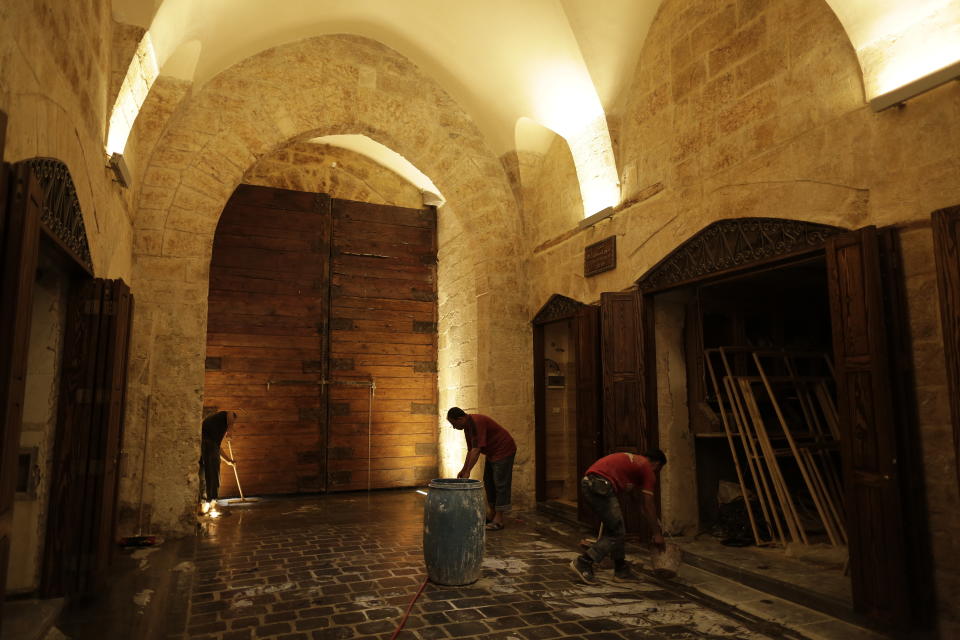 In this Saturday, July 27, 2019 photo, Syrian workers work on the newly renovated al-Saqatiyah Market in the old city of Aleppo, Syria. Much of Aleppo's centuries-old covered market is still in ruins but slowly small parts of it have been renovated where business is slowly coming back to normal nearly three years after major battles in Syria's largest city and once commercial center came to an end. (AP Photo/Hassan Ammar)