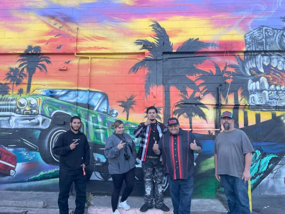 Jose “Hocus” Manriquez (center) with Johnny’s Market Manager Malek Shahibi, daughter Zsa Manriquez, son Zayvian Manriquez and painter Leon Henry in front of their mural on H Street in Modesto, Calif., Monday, Nov. 27, 2023.