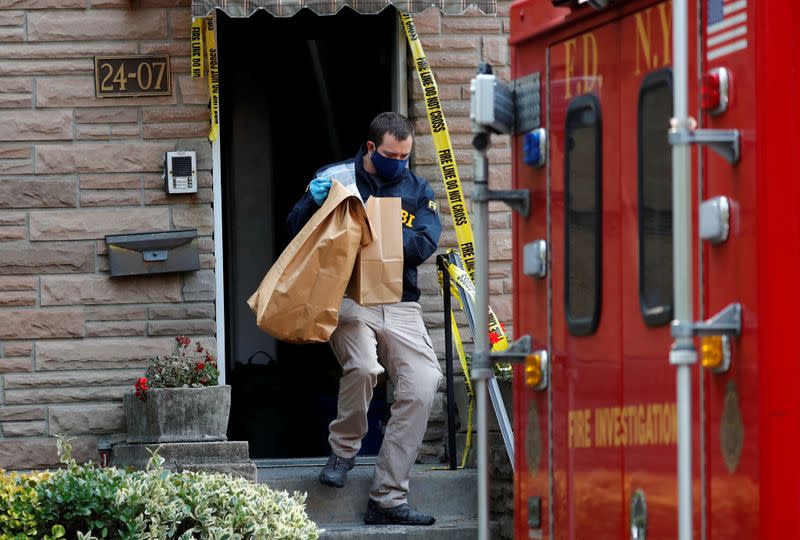 FBI officer removes evidence bags from a house where police say bomb-making materials were found, in New York