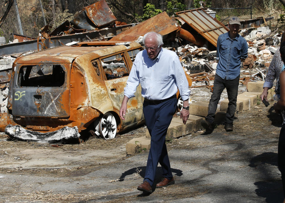 Democratic presidential candidate Sen. Bernie Sanders, I-Vermont, walks past a burned out vehicle as he tours a mobile home park that was destroyed by last year's wildfire in Paradise, Calif., Thursday, Aug. 22, 2019. Sanders released a $16.3 trillion climate plan Thursday that builds on the Green New Deal and calls for the United States to move to renewable energy across the economy by 2050 and declare climate change a national emergency. (AP Photo/Rich Pedroncelli)