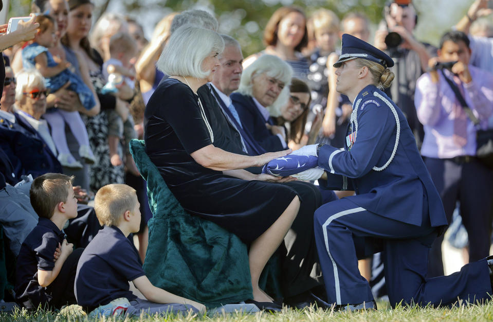 Air Force Capt. Jennifer Lee, right, kneels as she presents an American flag to Terry Harmon