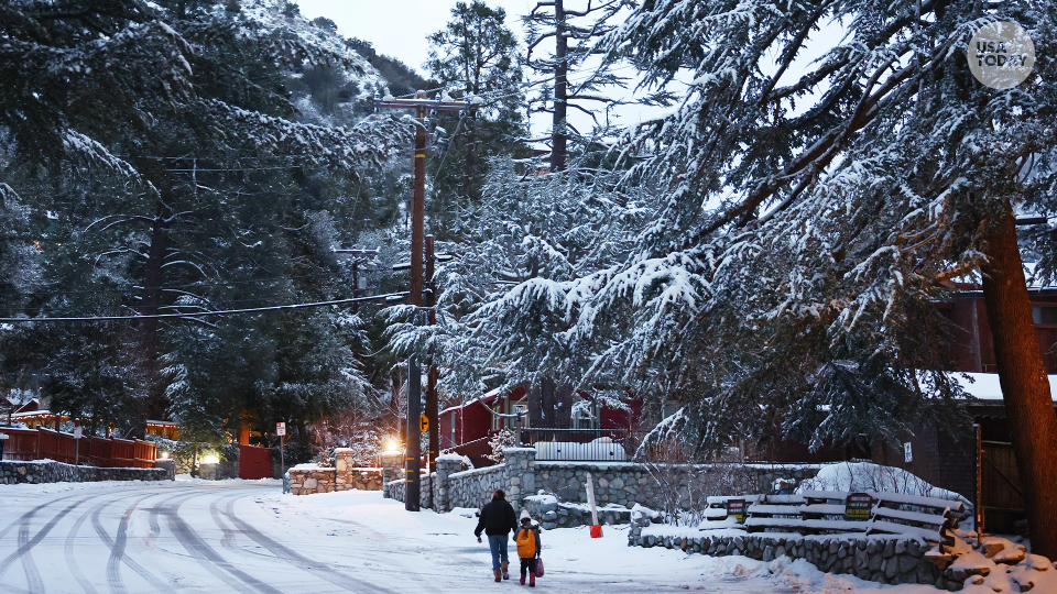 People walk as snow blankets the town in the San Gabriel Mountains, in San Bernardino County along the border of Los Angeles County, on February 23, 2023 in Mount Baldy, California.