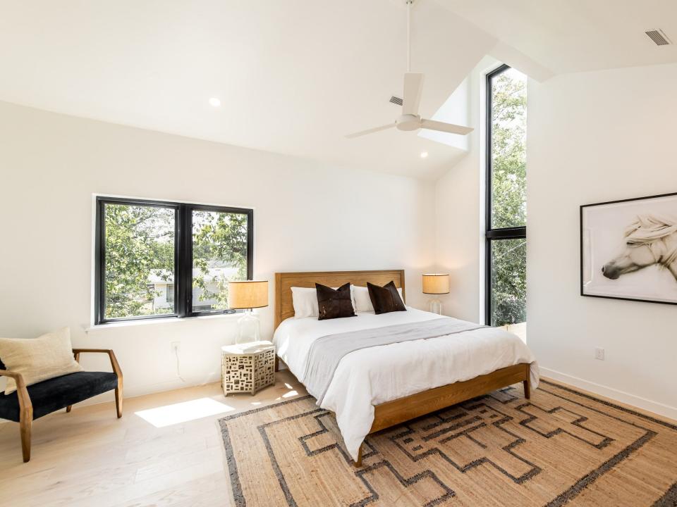 a bedroom with a bed and large windows