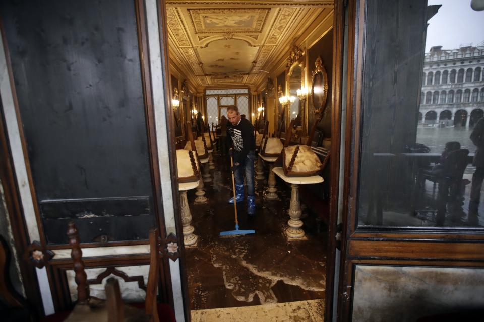 A man cleans water out of the historical Florian cafe, in Venice, Wednesday, Nov. 13, 2019. The high-water mark hit 187 centimeters (74 inches) late Tuesday, Nov. 12, 2019, meaning more than 85% of the city was flooded. The highest level ever recorded was 194 centimeters (76 inches) during infamous flooding in 1966. (AP Photo/Luca Bruno)