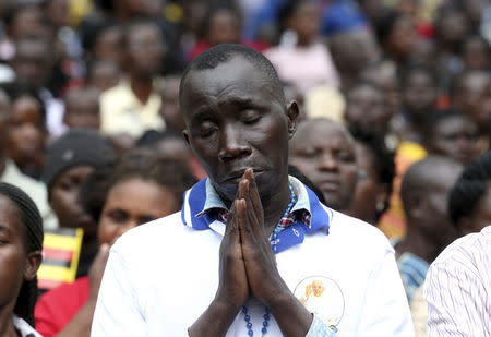 A faithful prays as Pope Francis leads a mass in Kampala, Uganda, November 28, 2015. REUTERS/Stefano Rellandini