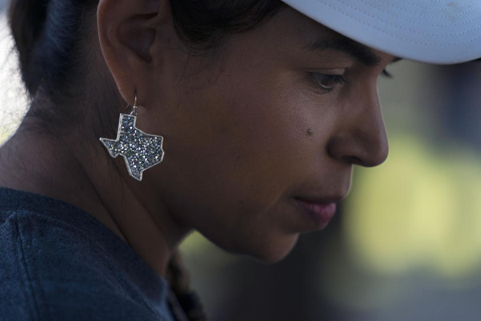 Ana Hernandez, a kindergarten teacher visiting from Dilley, Texas, wears an earring in the shape of Texas to show her support for the community while visiting a memorial in Uvalde, Texas, Friday, June 3, 2022. "Changes have to be done for us to feel secure in a classroom as a teacher (and) for students also to feel secure and safe in a classroom," said Hernandez. (AP Photo/Jae C. Hong)