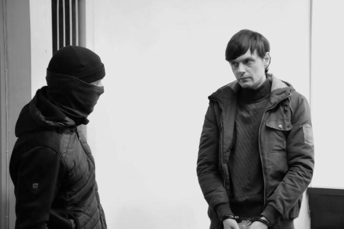 Artem Zinchenko, in handcuffs, with a man in a balaclava.