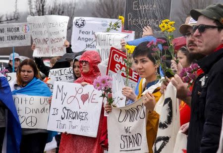 Demonstrators against U.S. Republican presidential candidate Donald Trump stand in the rain outside of a rally in Cincinnati, Ohio, March 13, 2016. REUTERS/William Philpott