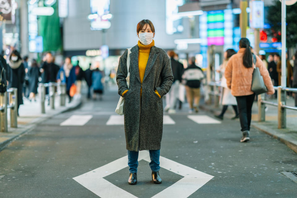 A portrait of a young woman wile wearing a face mask for protection from cold and flu and viruses.