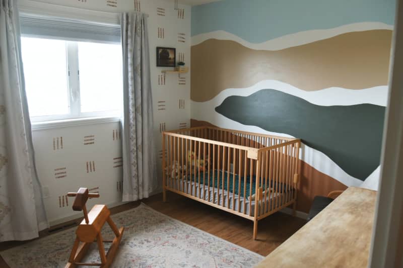 White nursery with gold, blue and green paint and wallpaper design and wood crib