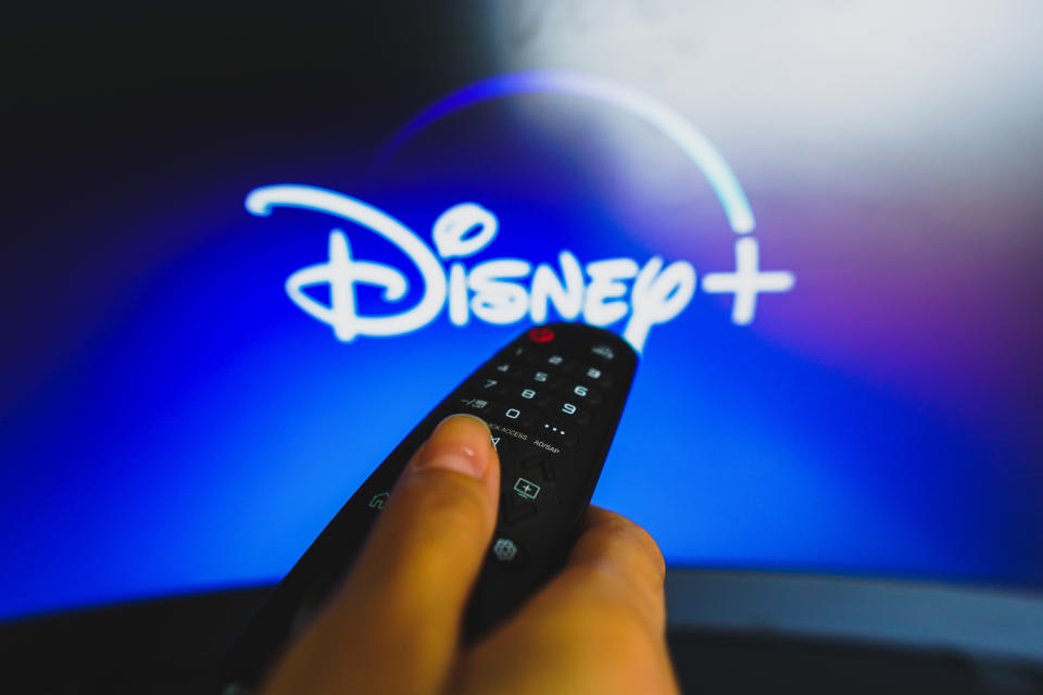 BRAZIL - 2022/05/10: In this photo illustration, a hand holding a TV remote control in front of the Disney Plus logo on a TV screen. (Photo Illustration by Rafael Henrique/SOPA Images/LightRocket via Getty Images)