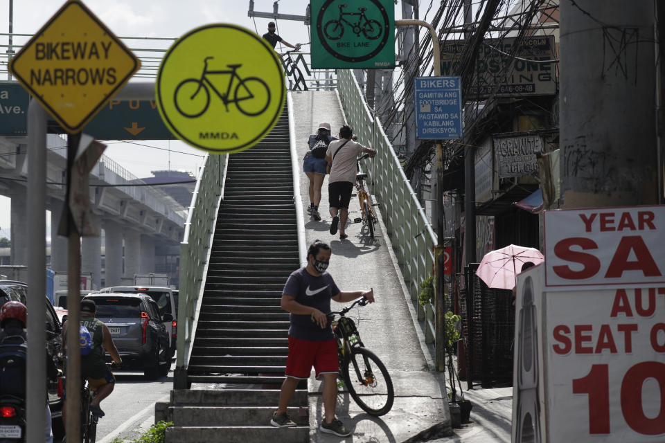 Residents push their bicycles up a bridge as public transportation still remains unavailable during the community quarantine on the outskirts of Manila, Philippines on Monday, May 18, 2020. Crowds and vehicular traffic returned to shopping malls in the Philippine capital after a two-month coronavirus lockdown was partially relaxed over the weekend, prompting police to warn of arrests and store closures. (AP Photo/Aaron Favila)