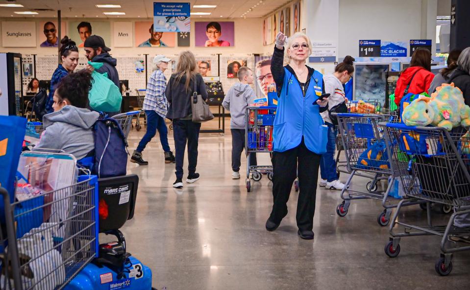 Joanne Moore, self-checkout associate, waves for customers to come toward open stations at a Walmart store in Loveland on Oct. 13.
