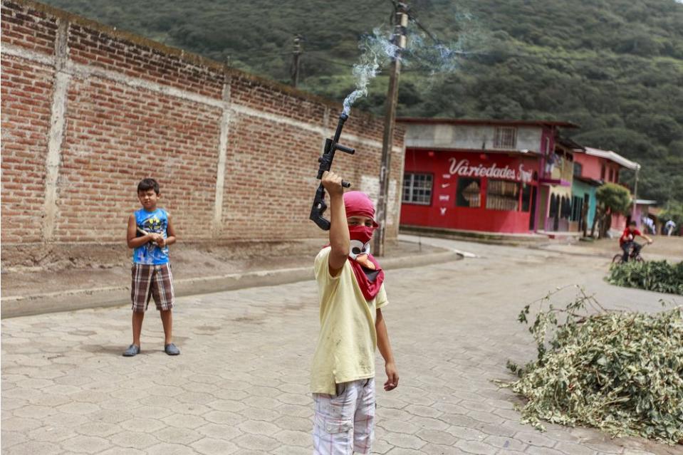 A child with a toy gun—fitted with a firework that emits smoke—pretend to guard a barricade in La Trinidad, a municipality north of Managua, on June 28.