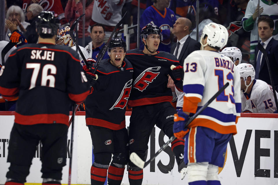 Carolina Hurricanes' Martin Necas, center right, celebrates after his empty-net goal with teammate Jack Drury, center left, and Brady Skjei (76) as New York Islanders' Mathew Barzal (13) skates by during the third period in Game 1 of an NHL hockey Stanley Cup first-round playoff series in Raleigh, N.C., Saturday, April 20, 2024. (AP Photo/Karl B DeBlaker)