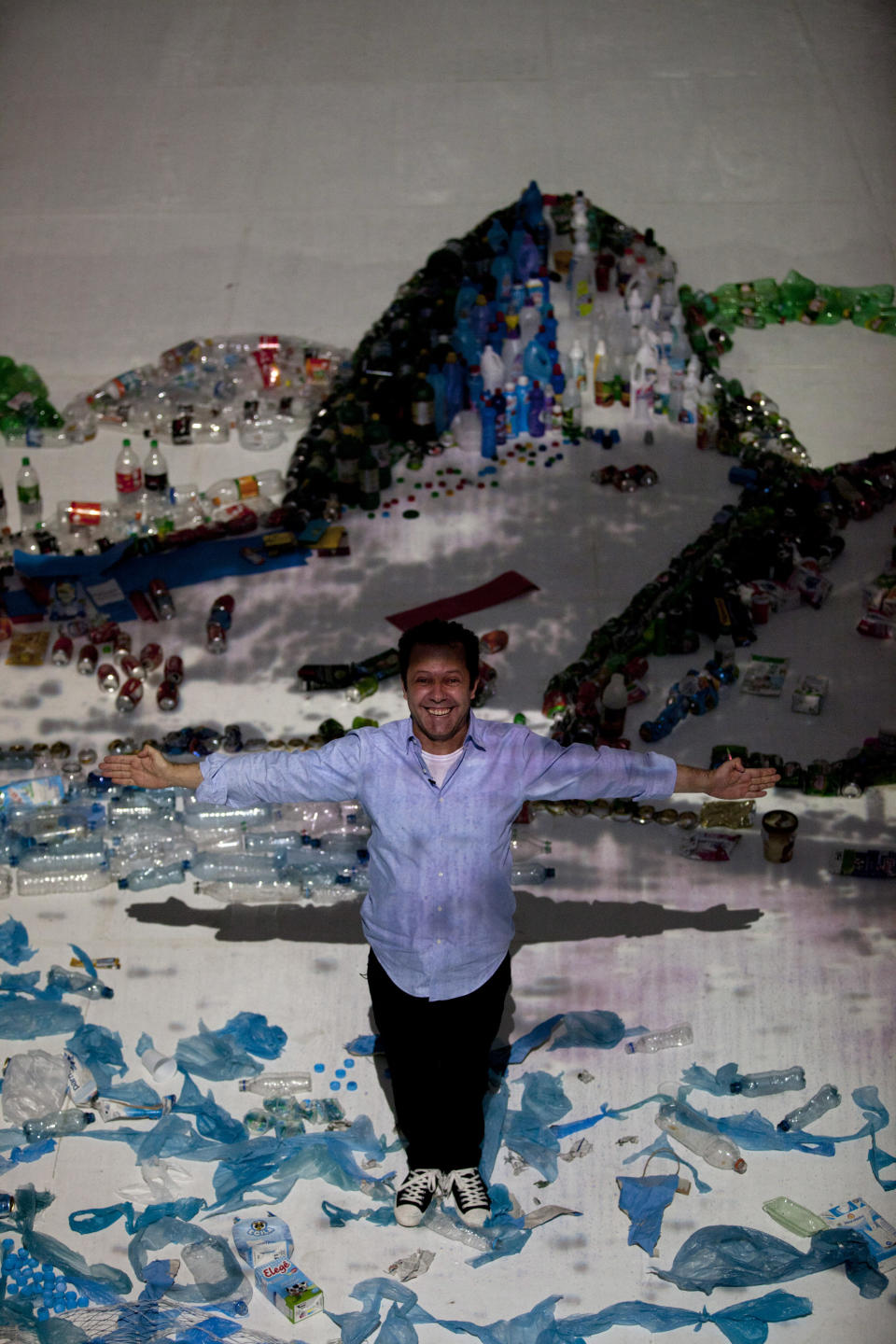 Brazilian artist Vik Muniz poses for a photo as he stands in his "Landscape" project that uses waste to recreate the image of Guanabara Bay in Rio de Janeiro, Brazil, Saturday, June 16, 2012. Muniz's project recreates city landmarks with recyclable materials donated by the public, who will be able to take their waste to the installation's tent between June 15 and 22, on the sidelines of the UN Conference on Sustainable Development, or Rio+20. (AP Photo/Silvia Izquierdo)