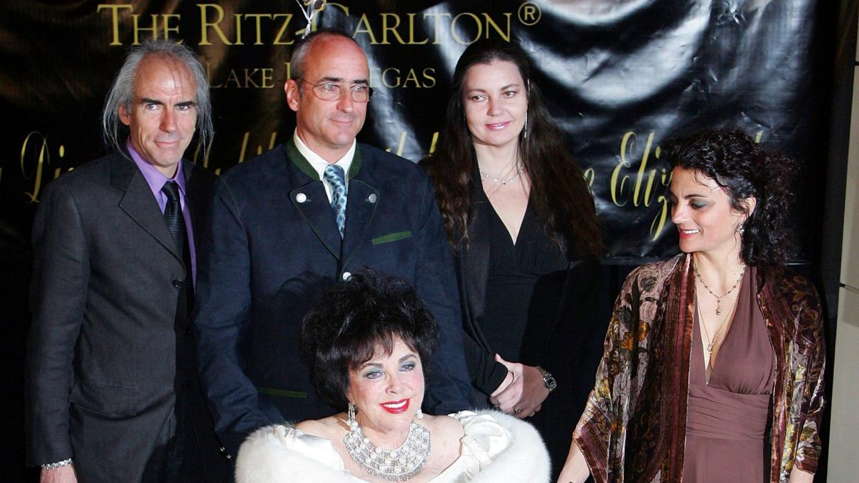 Elizabeth Taylor in a white dress and wheelchair with her four children