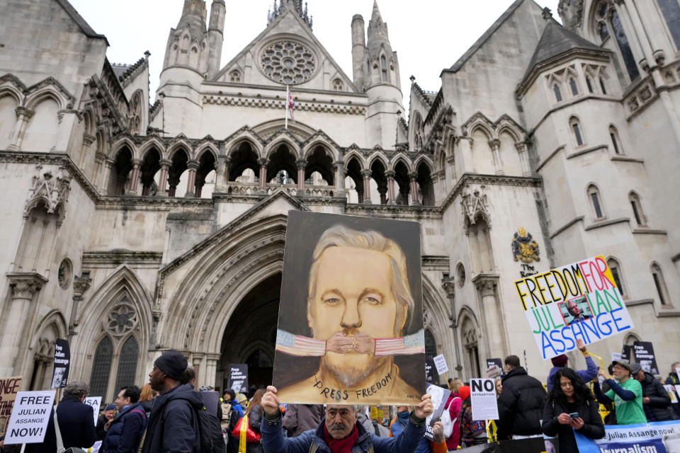 Artist Kaya Mar holds up his painting of Julian Assange as demonstrators hold banners outside the Royal Courts of Justice in London, Tuesday, Feb. 20, 2024. WikiLeaks founder Julian Assange will make his final appeal against his impending extradition to the United States at the court. (AP Photo/Kirsty Wigglesworth)