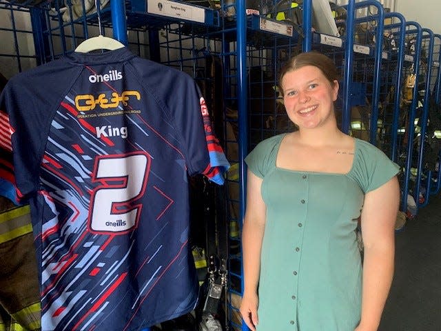 Reaghan King stands next to her rugby jersey by her locker at the Clayton Fire Station, where she is a volunteer firefighter.