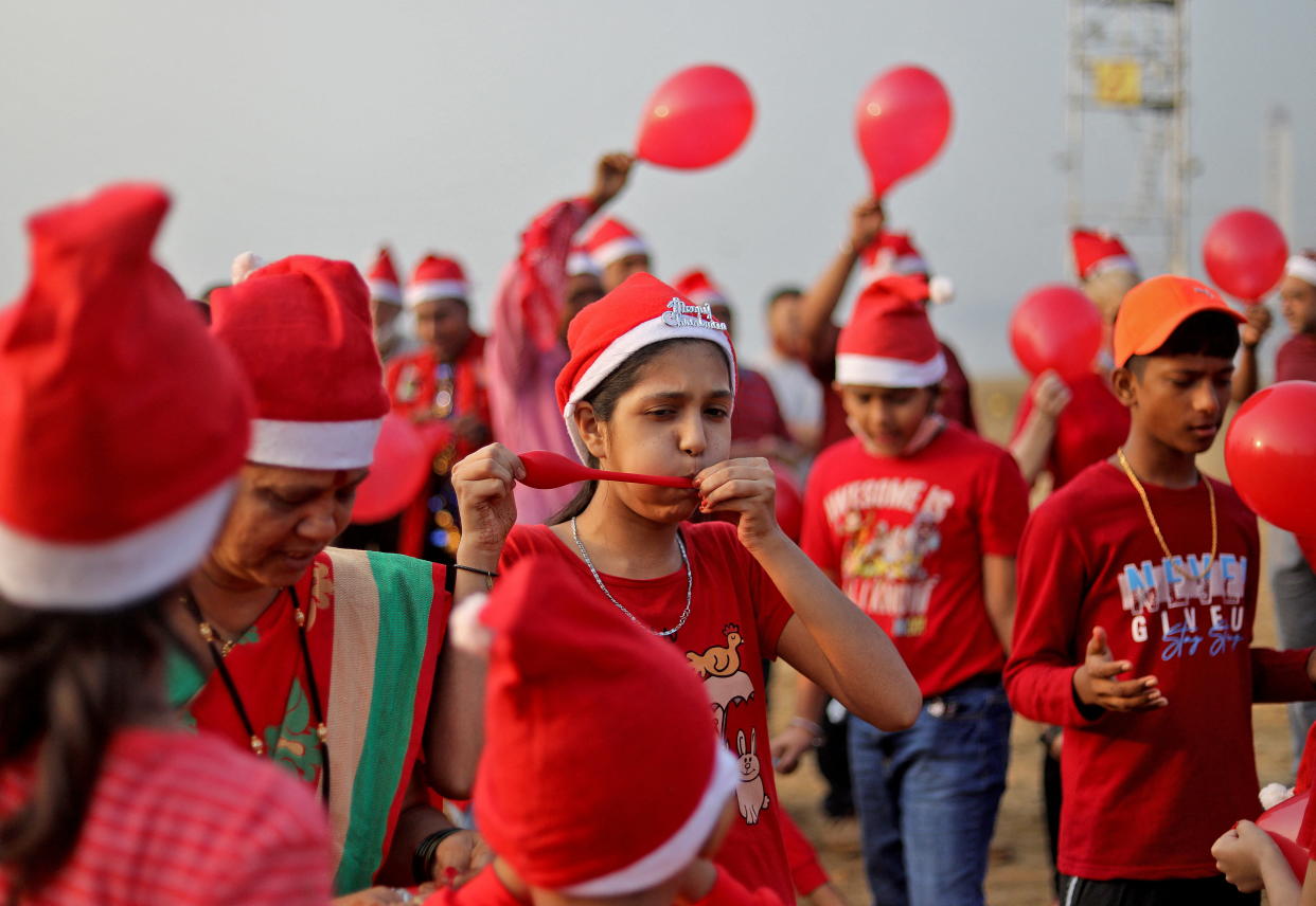 A girl wearing a Santa hat blows up a balloon as she takes part in a laughter yoga session during Christmas celebrations on a beach in Mumbai, India, December 25, 2021. REUTERS/Niharika Kulkarni
