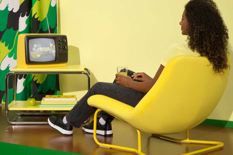 Person watching vintage t.v on Ikea coffee table in yellow Ikea chair.