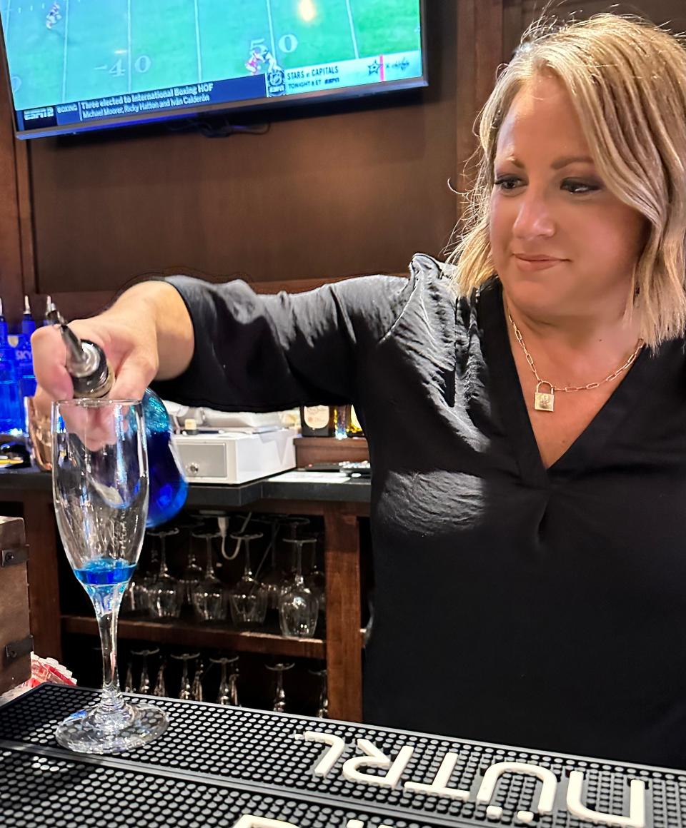 Melissa, a bartender at Fronimo's Downtown in Canton, works on the Grinch bellini.