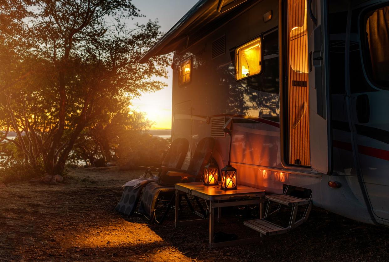 Road Trip Adventures. Calm Warm Night on a Camping. Camper Van, Outdoor Chairs and Romantic Light From Lanterns. Vacation in Recreational Vehicle.