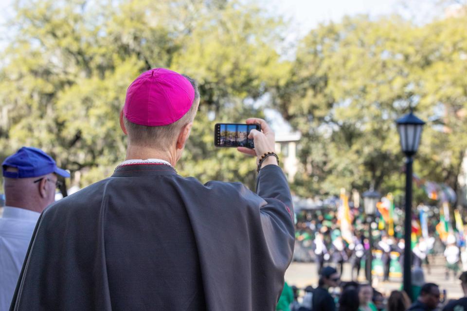 Bishop Stephen D. Parkes takes a photo of the 200th St. Patrick's Day Parade as it approaches the Cathedral Basilica of St. John the Baptist.