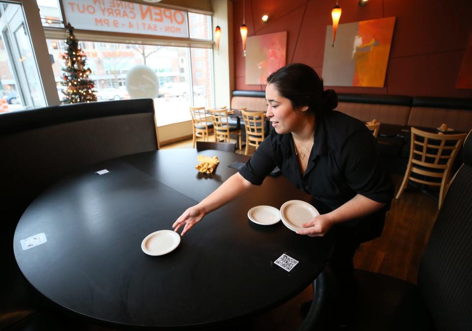Server/bartender Zahra Yusufi sets a table at Crave in downtown Akron.