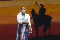 Lemiley Lane, a Bountiful junior who grew up in the Navajo Nation in Arizona, walks along the campus near a a mural of an Indigenous man meant to represent the Braves mascot at Bountiful High School, July 21, 2020, in Bountiful, Utah. While advocates have made strides in getting Native American symbols and names changed in sports, they say there's still work to do mainly at the high school level, where mascots like Braves, Indians, Warriors, Chiefs and Redskins persist. (AP Photo/Rick Bowmer)