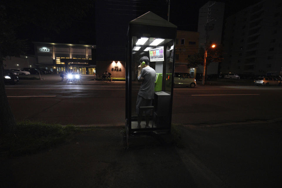 A man calls with a public phone in the blackout on the center of Sapporo city, Hokkaido, northern Japan, Thursday, Sept. 6, 2018. A powerful earthquake hit wide areas on Japan's northernmost main island of Hokkaido early Thursday, triggering landslides as well as causing the loss of power. (AP Photo/Eugene Hoshiko)