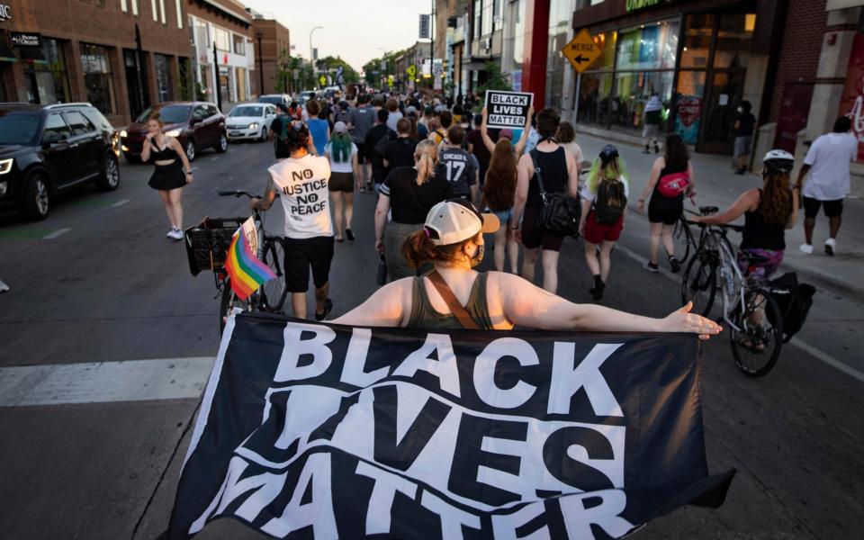 A woman holds a Black Lives Matter flag as community members march, Sunday, June 6, 2021, in Minneapolis, for Winston Boogie Smith Jr., who was fatally shot by members of a U.S. Marshals task force several days earlier.  - AP